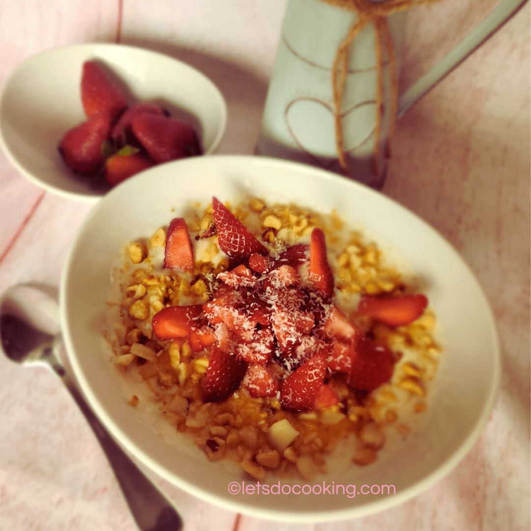 Frühlingsjoghurt mit Erdbeeren und Crunch in einer Schale, daneben frische Erdbeeren und eine Milchflasche