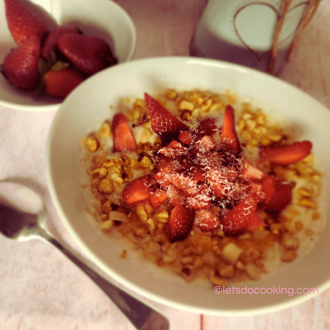 Frühlingsjoghurt in einer weißen Schale mit frischen Erdbeeren, Crunch und Kokosflocken